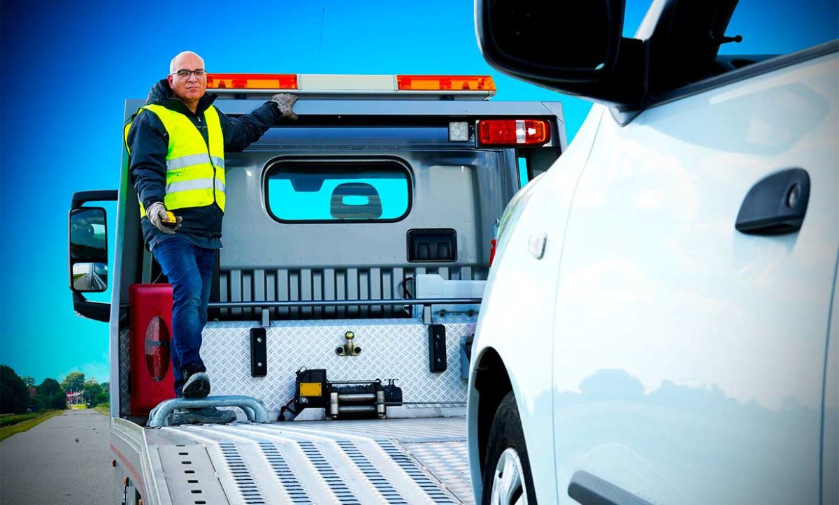 Man controlling a winch with a remote control on a Tow Truck - Tele Radio